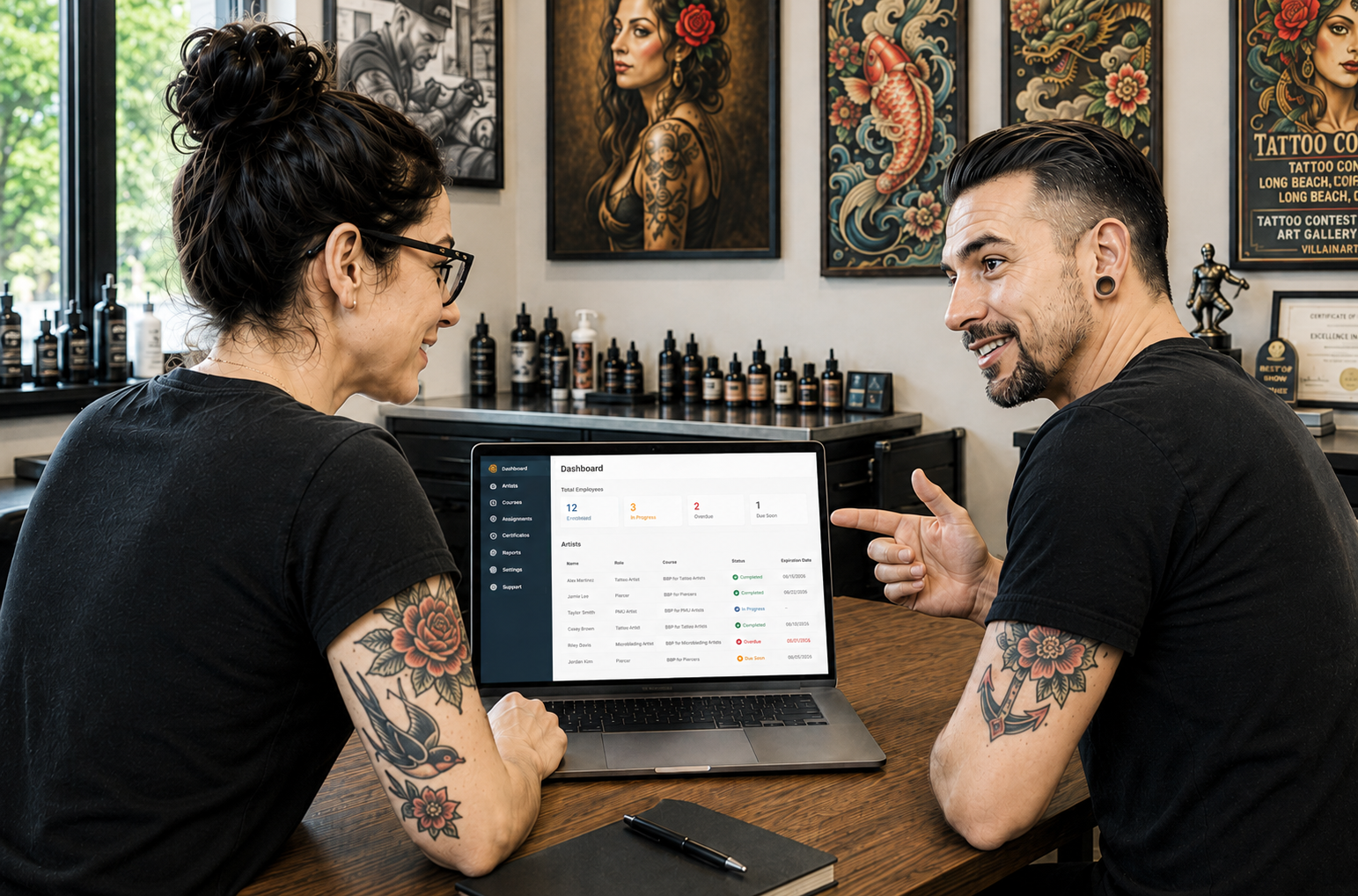 Tattoo shop owners reviewing BBP certification status on a laptop
