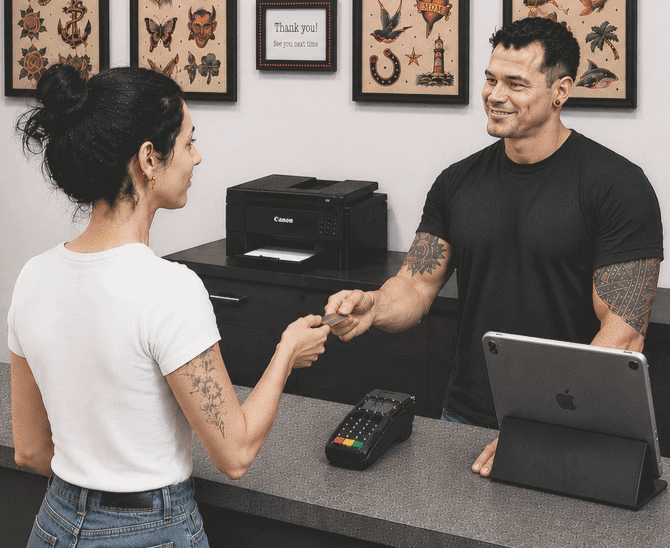 Tattoo artist assisting client at studio front desk as she pays after a professional, safety-focused tattoo session.